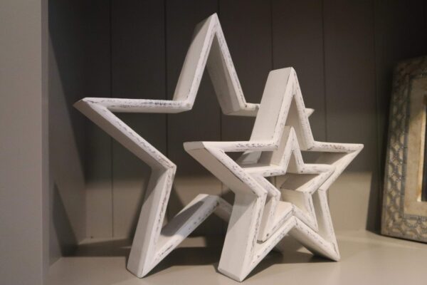 Set of three white wooden stars which vary in size with a distressed paint finish. Can be styled separately or inside one another.